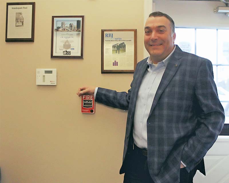 Craig Armitage, founder of C.M. Armitage Electrical Contracting, in the office with framed press articles behind him